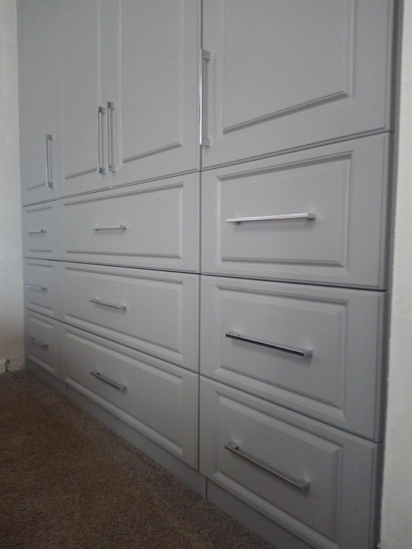 A row of white cabinets with drawers in a room.