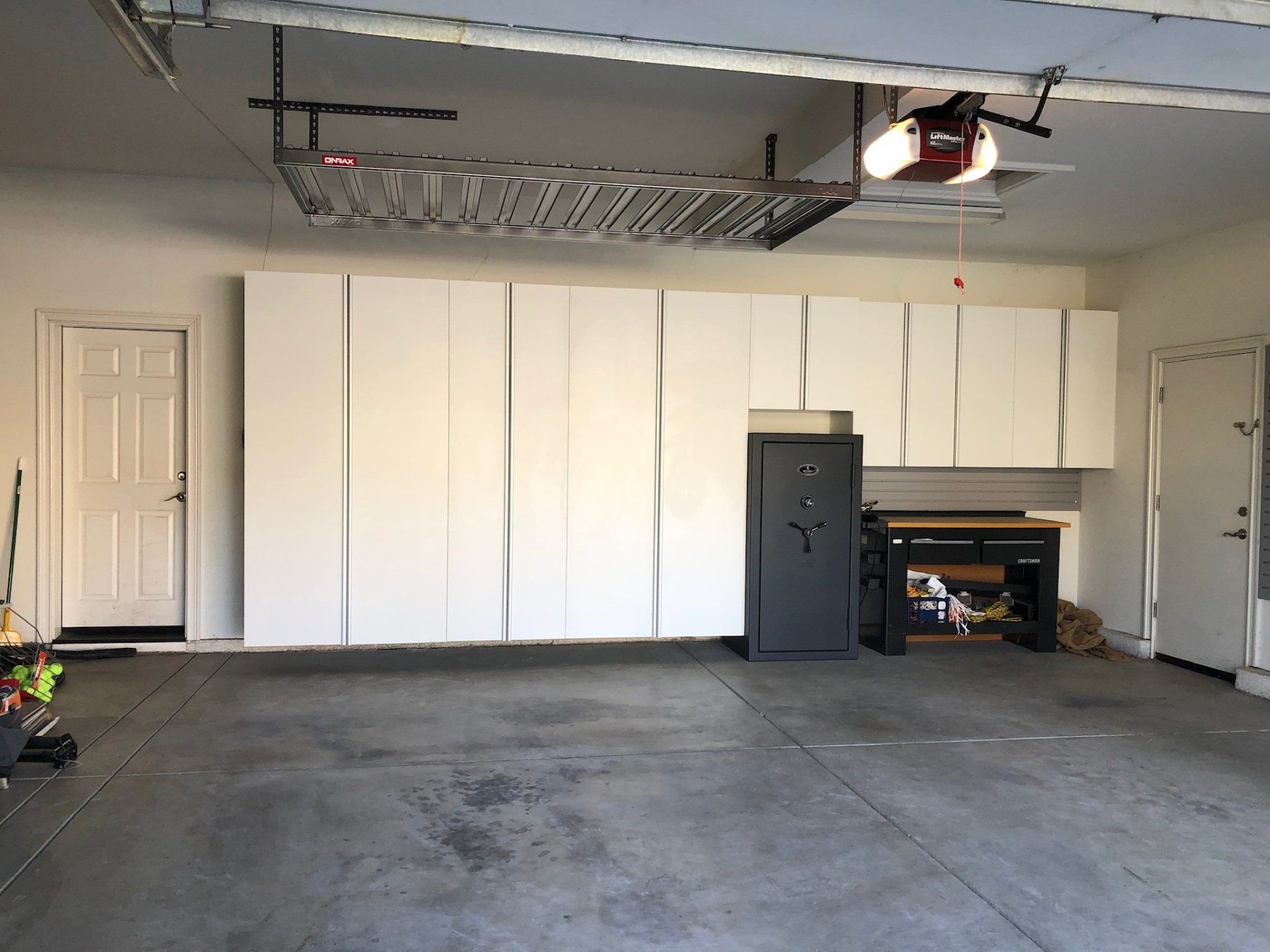 An empty garage with white cabinets and a safe