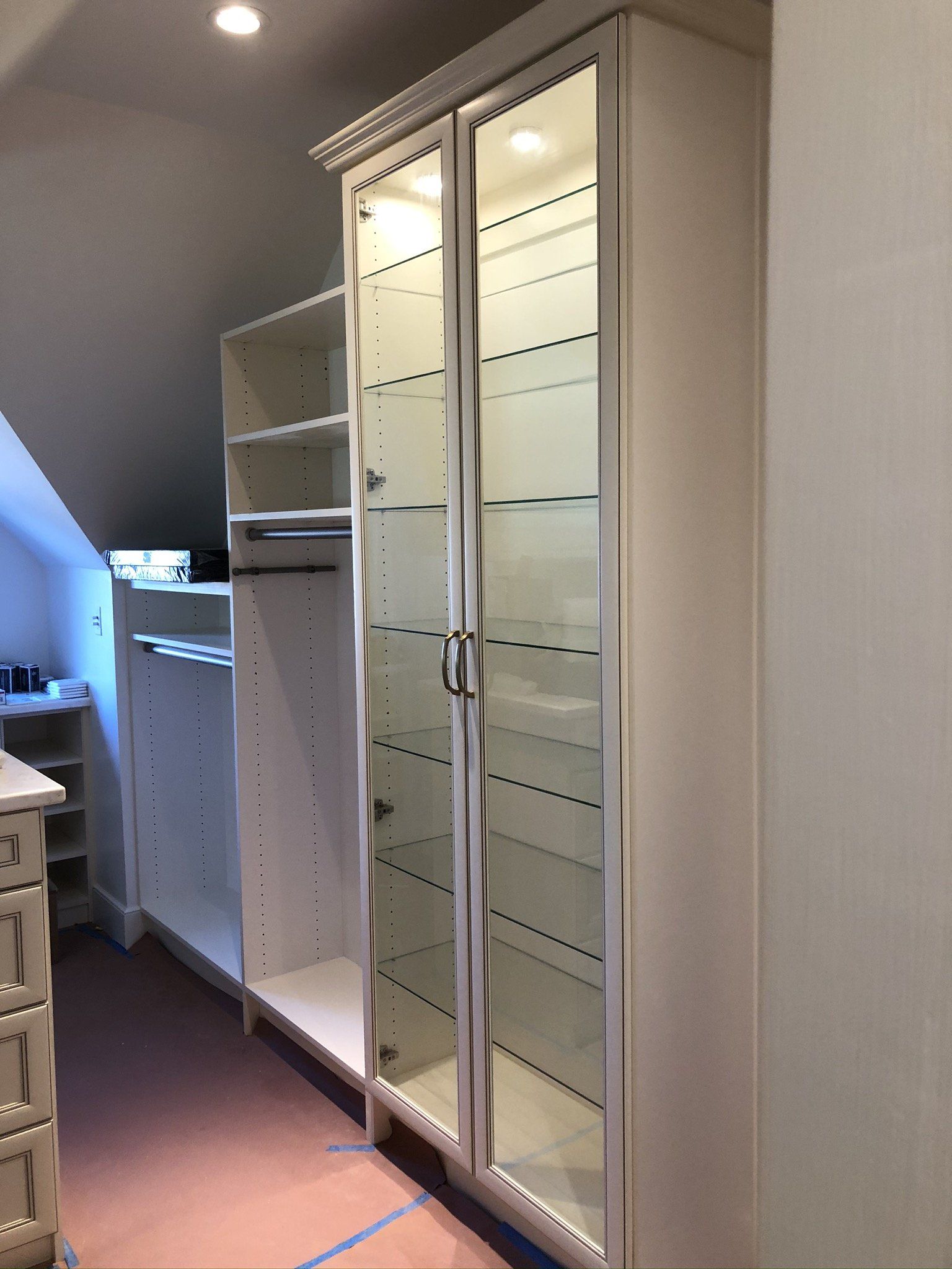 A walk in closet with glass doors and shelves