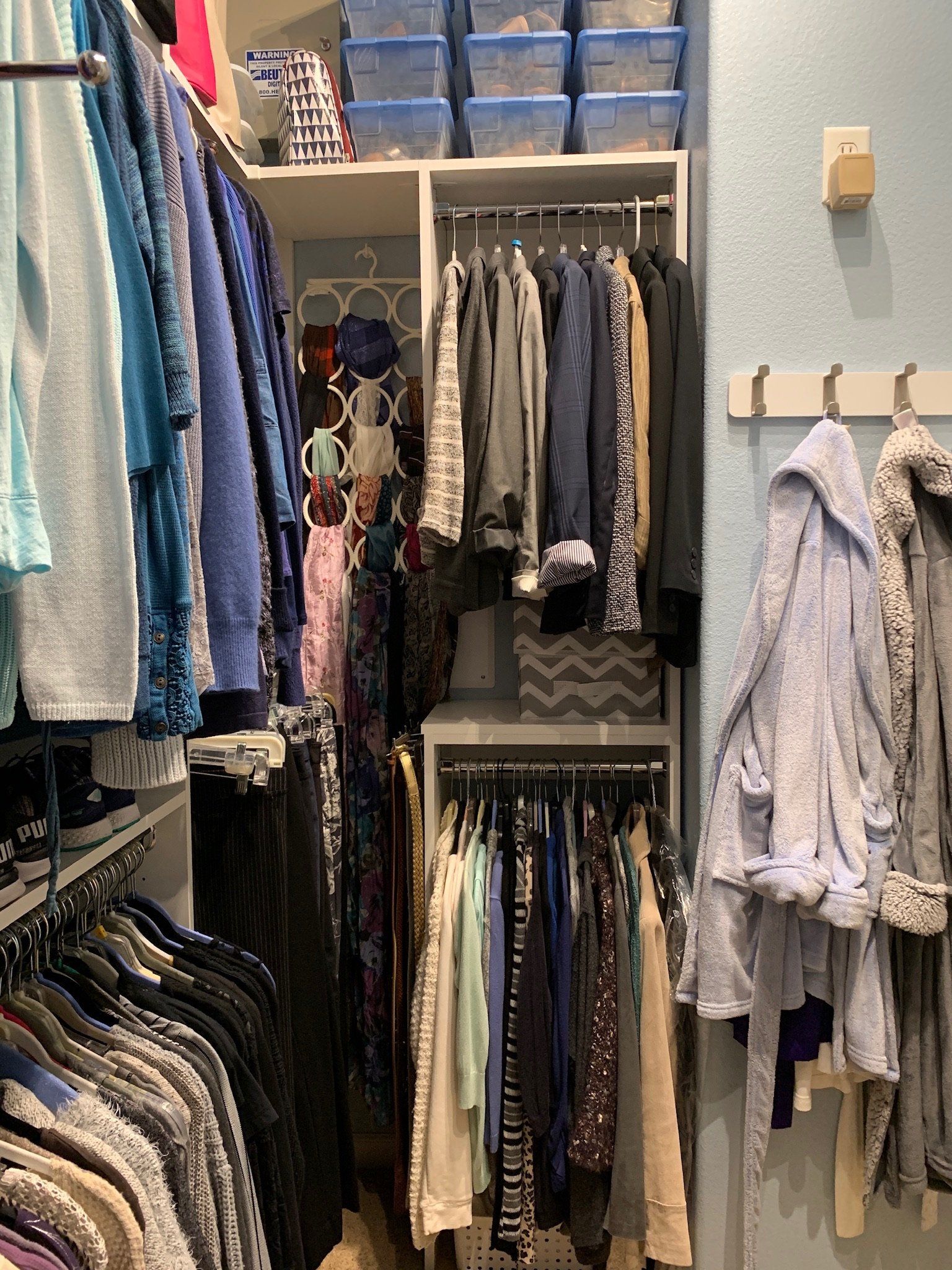 A walk in closet filled with lots of clothes hanging on racks.