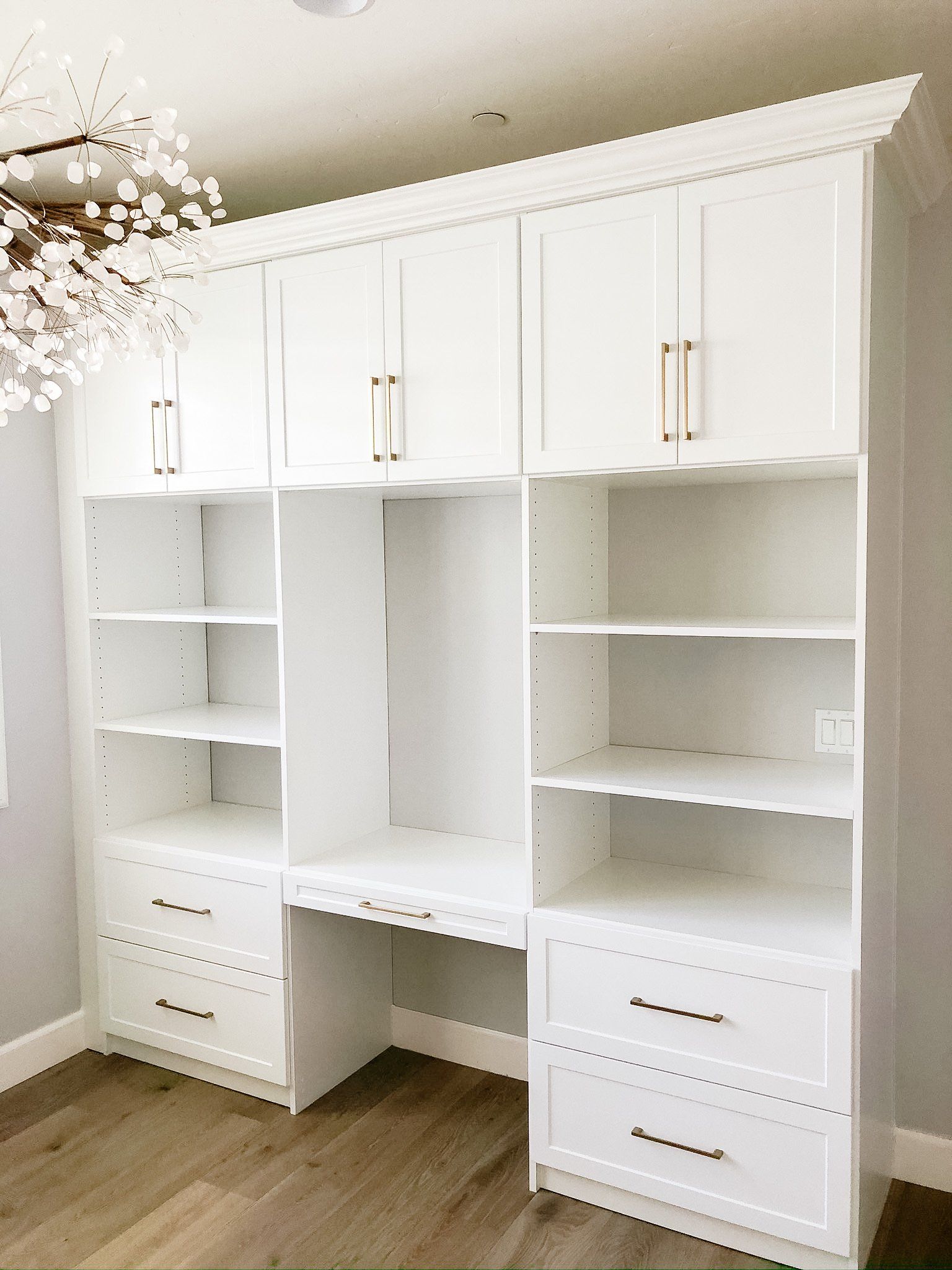 A room with white cabinets , shelves , drawers and a desk.