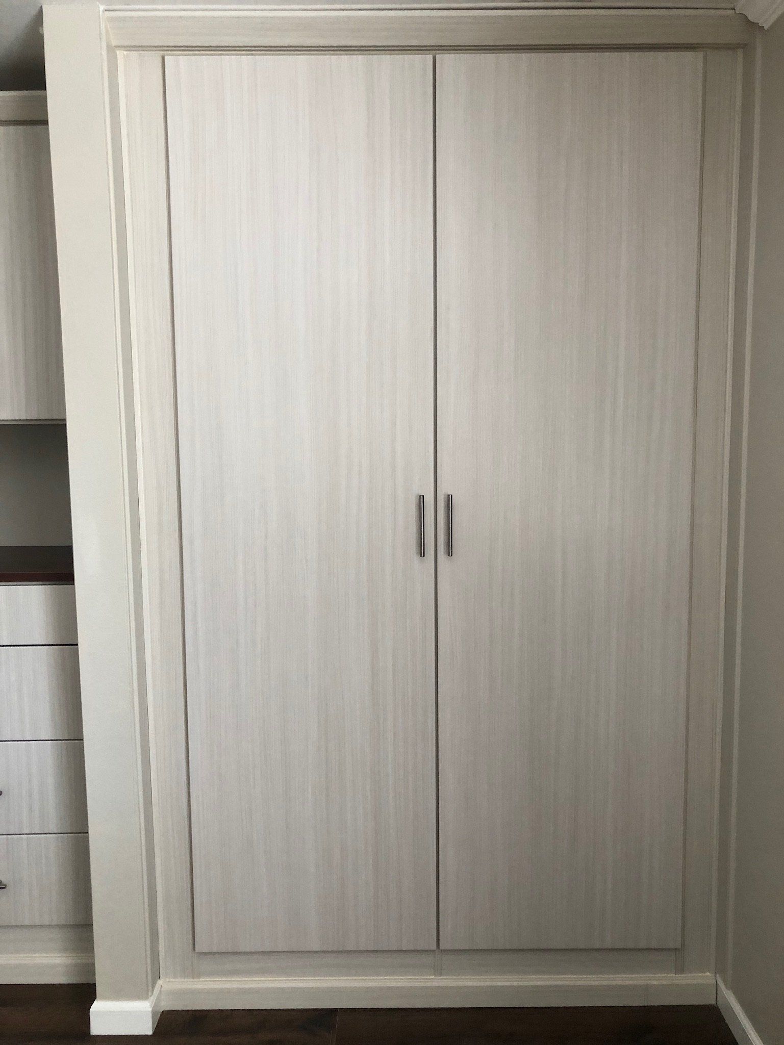 A white wardrobe with two doors in a room.