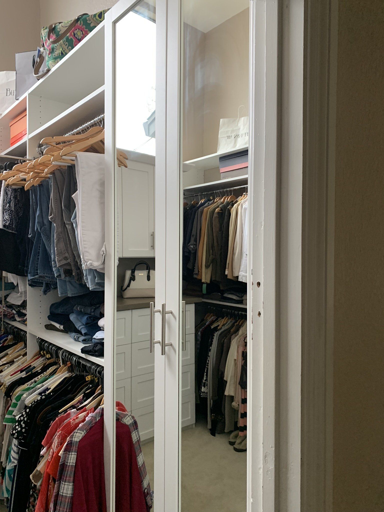 A walk in closet filled with clothes and a mirror.