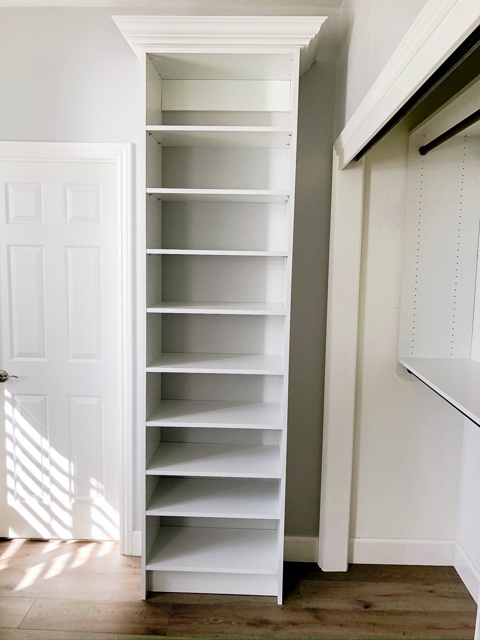 A white shoe rack is sitting in a closet next to a door.
