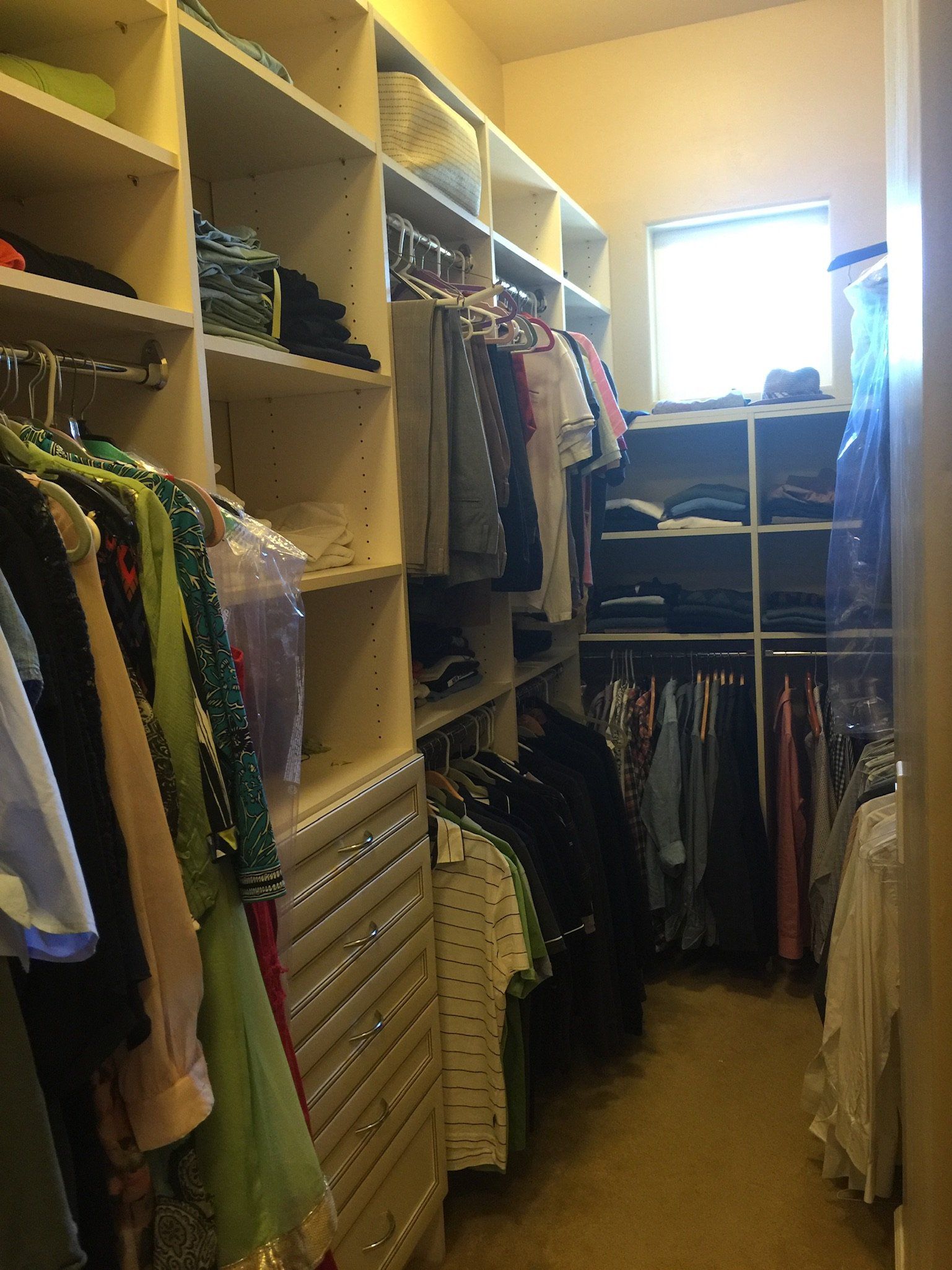A closet filled with lots of clothes and a window