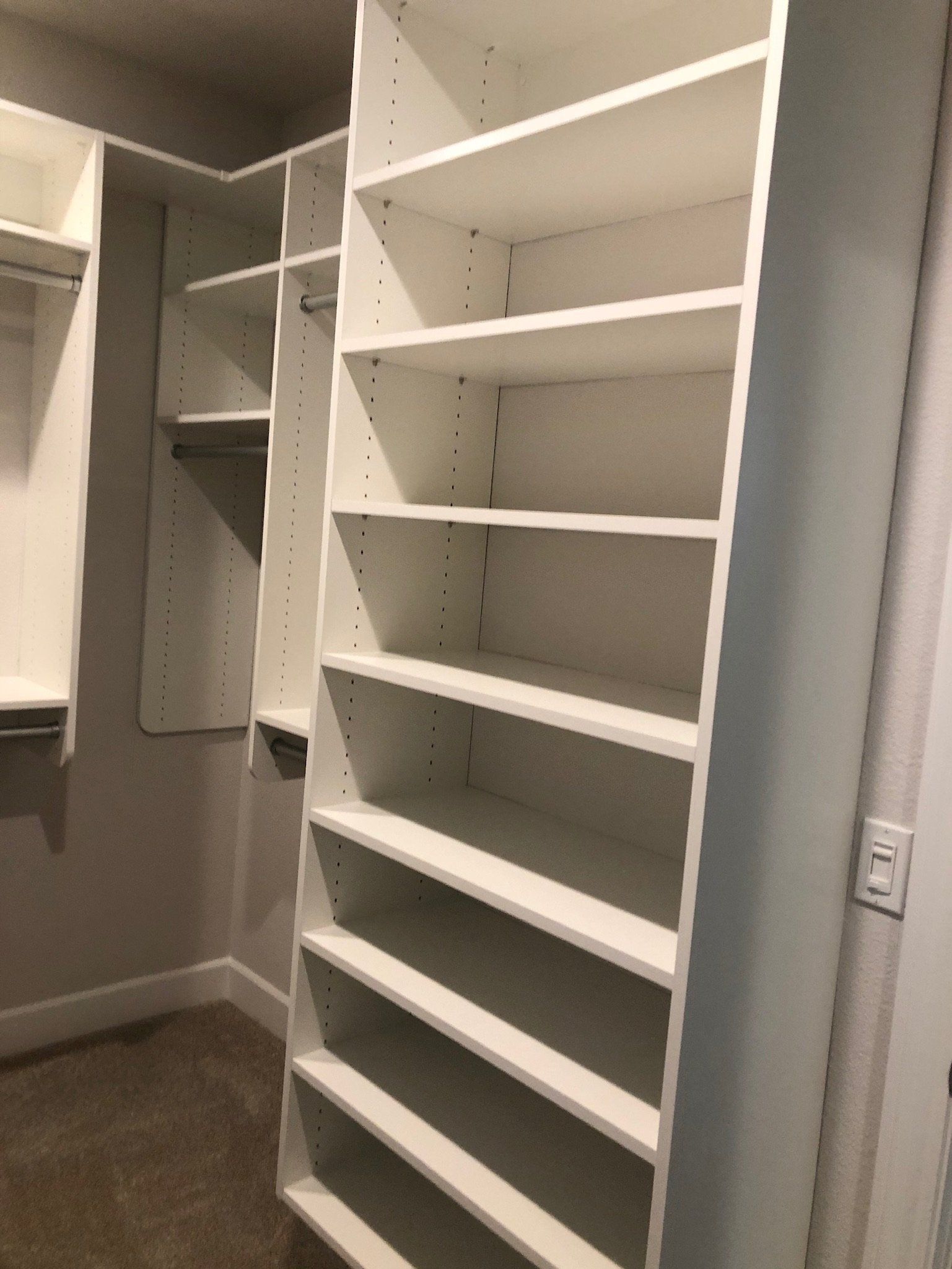 A walk in closet with lots of shelves and hooks