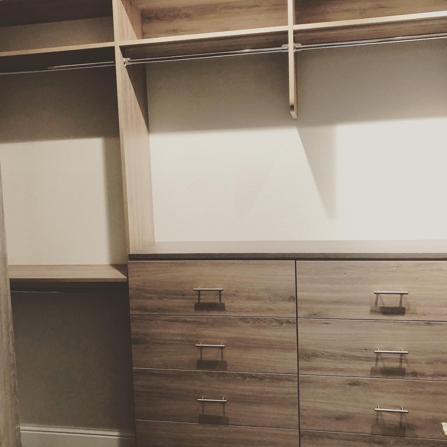 A walk in closet with wooden shelves and drawers
