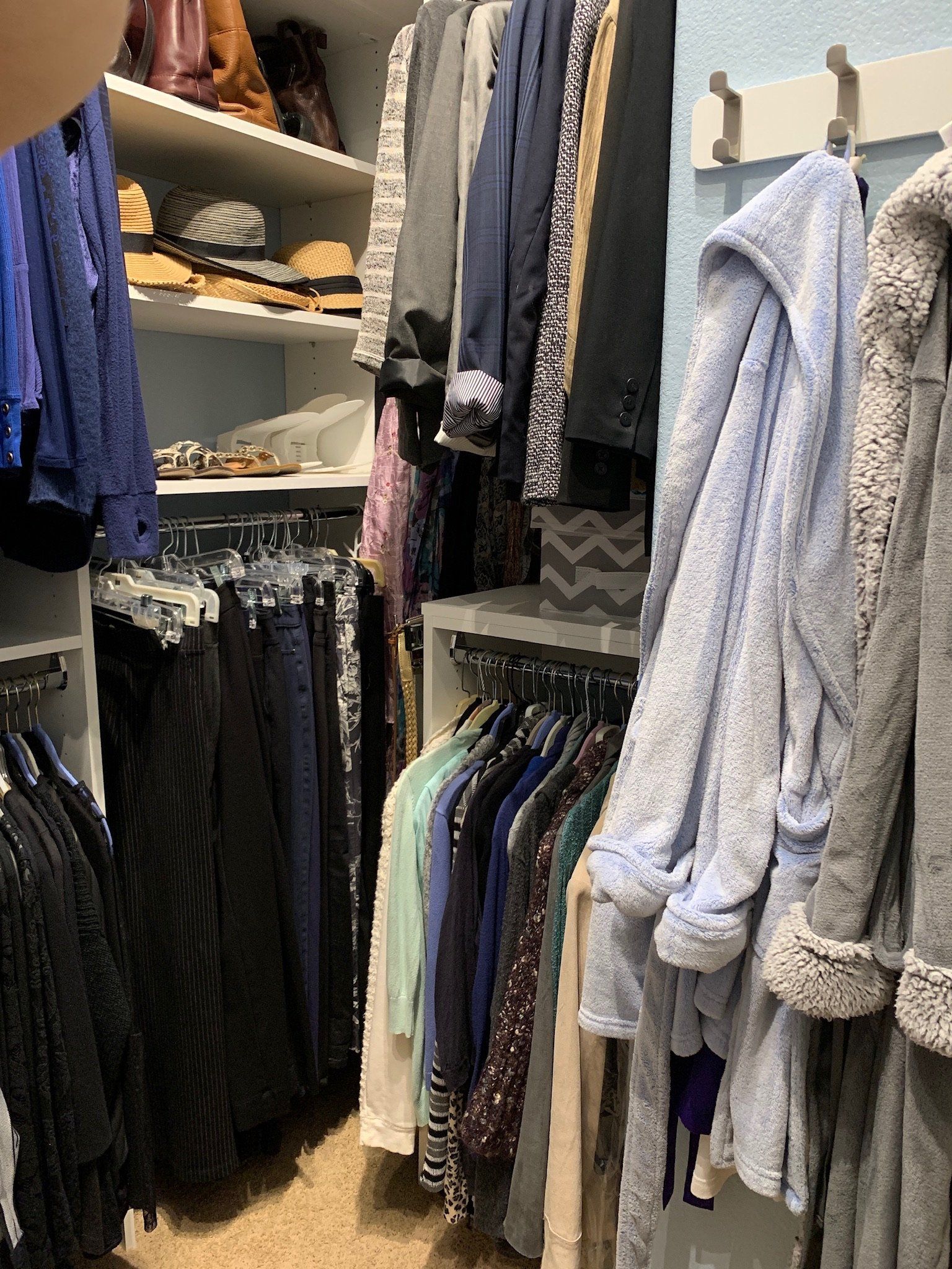 A closet filled with lots of clothes and a robe hanging on the wall.