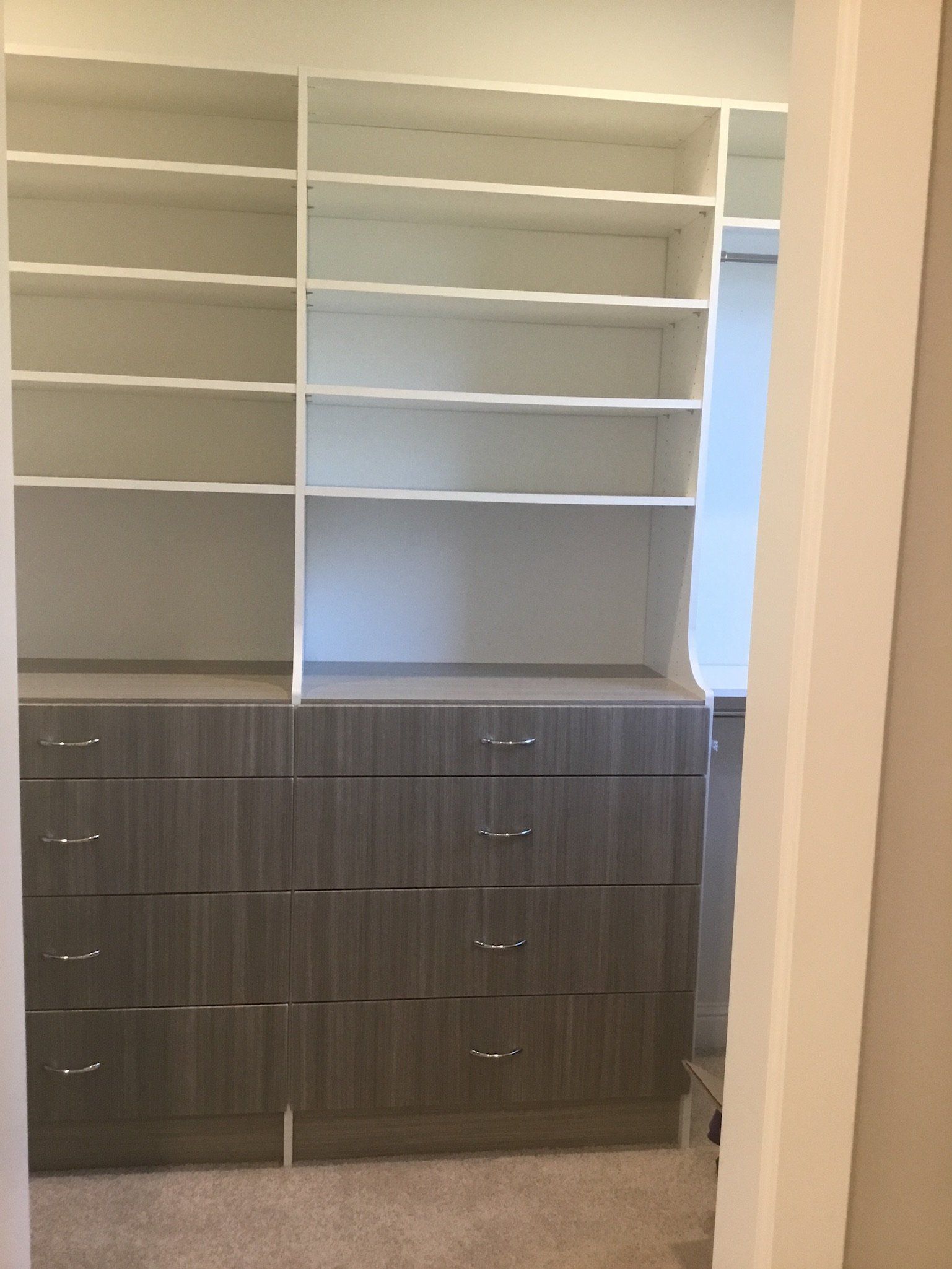 A walk in closet with lots of shelves and drawers