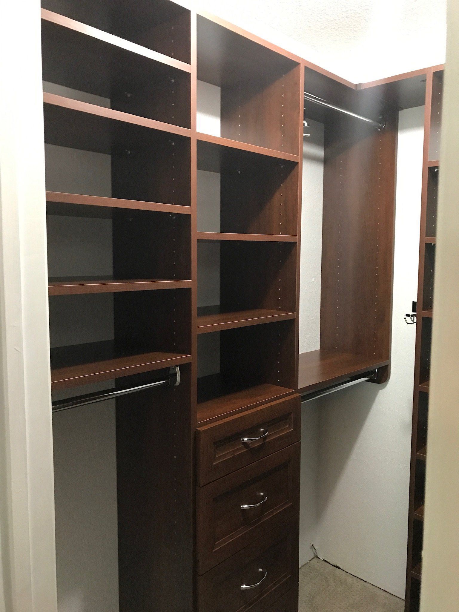 A walk in closet with lots of shelves and drawers