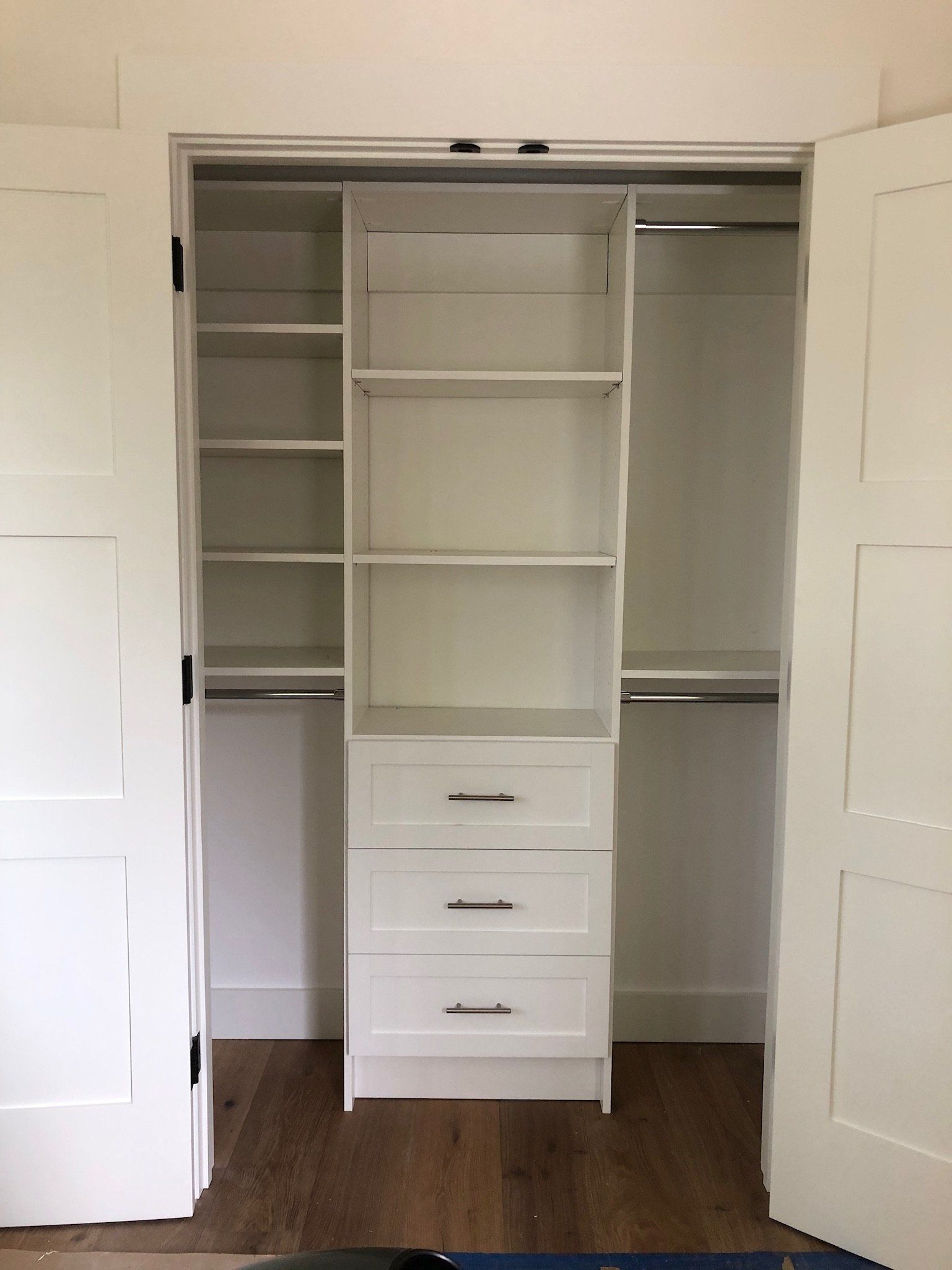 A white closet with shelves and drawers in a bedroom