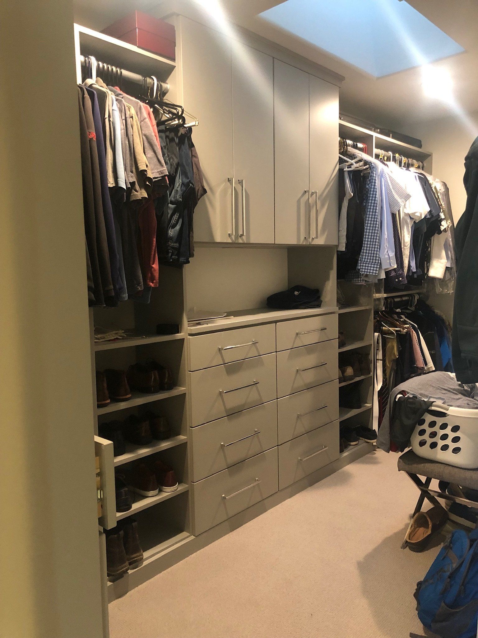 A walk in closet with lots of clothes and a laundry basket