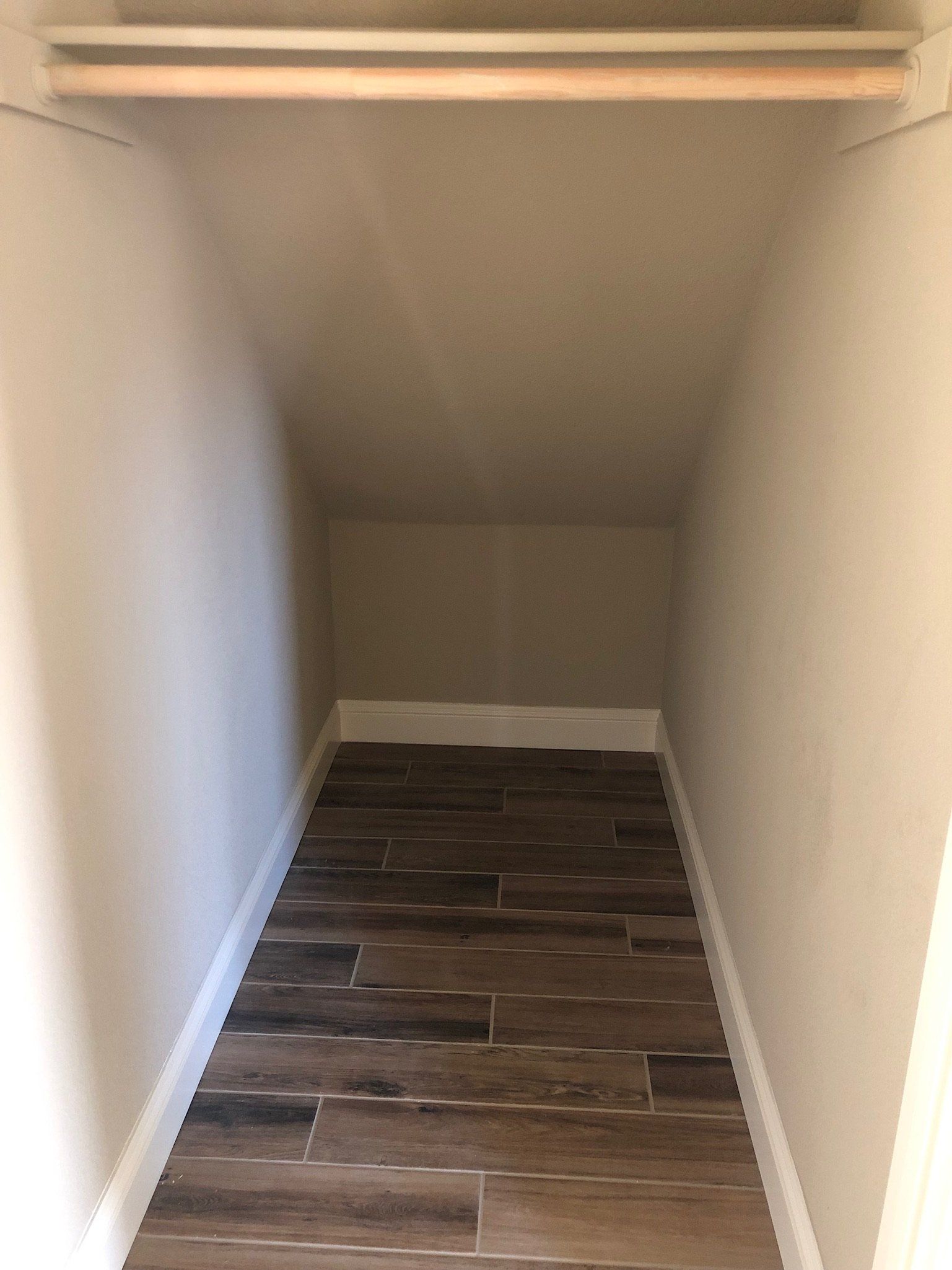 A small closet with a wooden floor and a shelf.