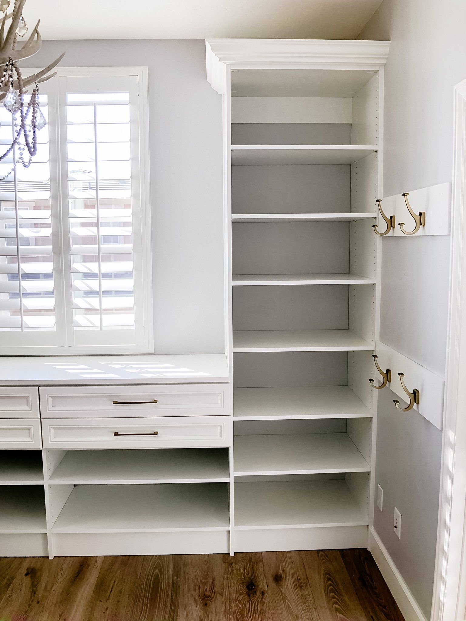 A room with a lot of shelves and a window.