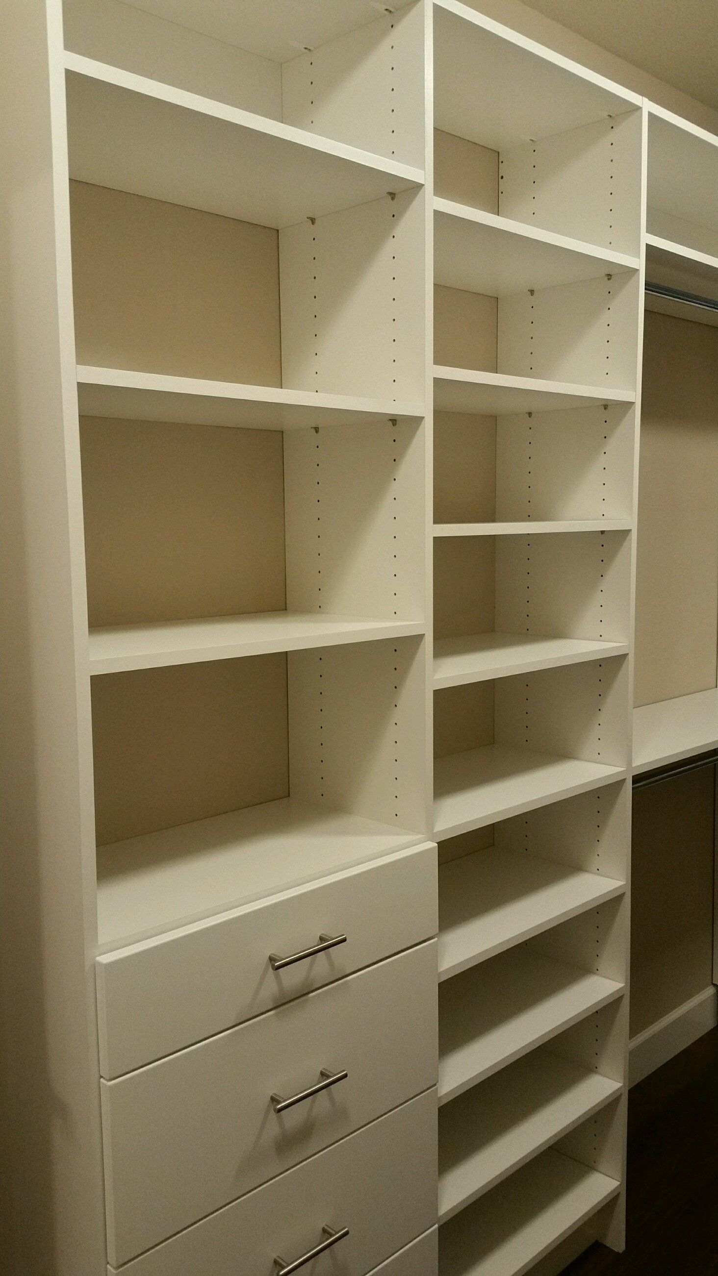 A walk in closet with lots of shelves and drawers.