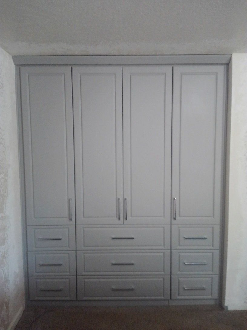 A large white wardrobe with drawers and doors in a bedroom.