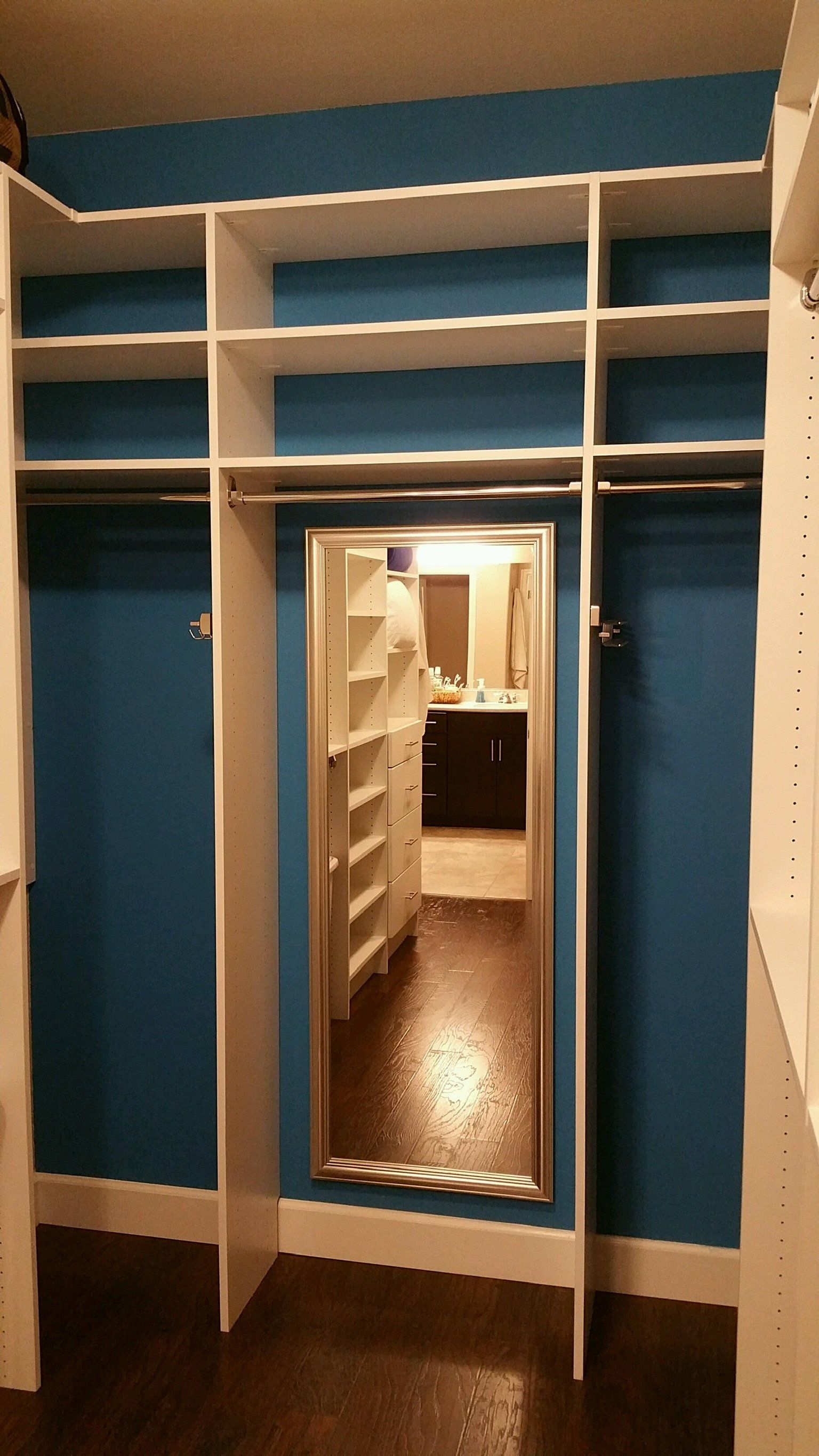 A walk in closet with blue walls and a mirror