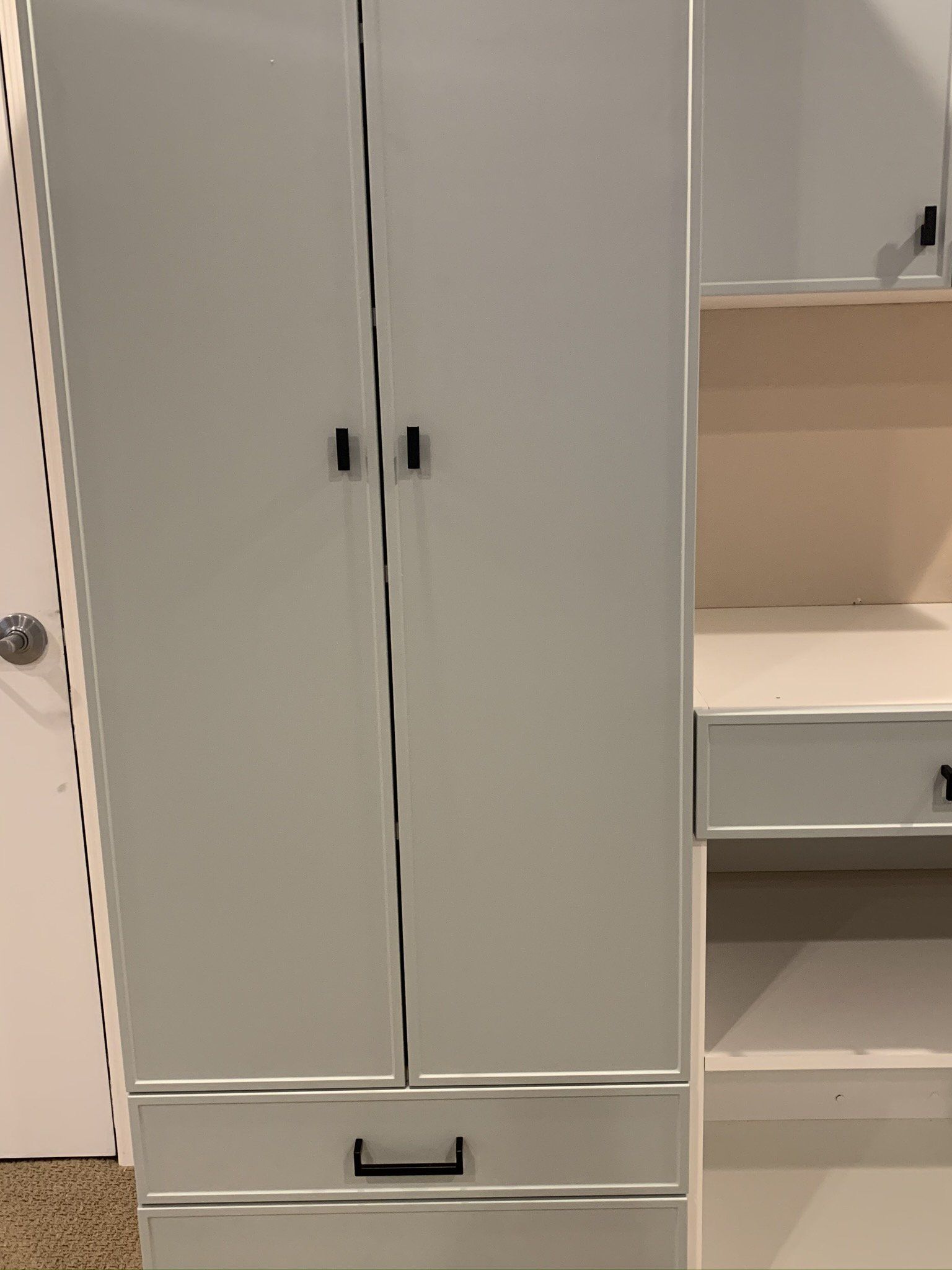 A white wardrobe with drawers and a desk in a room.