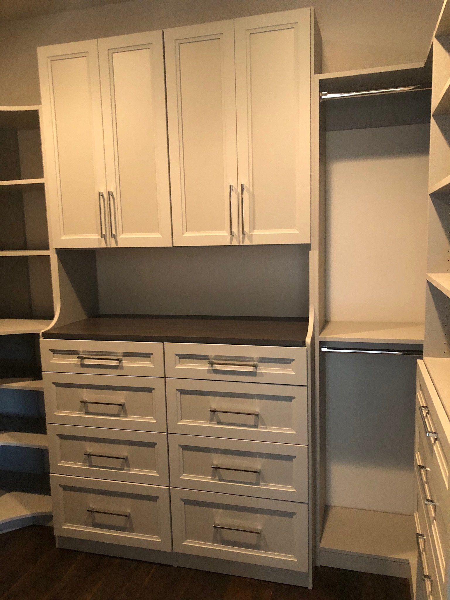 A walk in closet with white cabinets and drawers