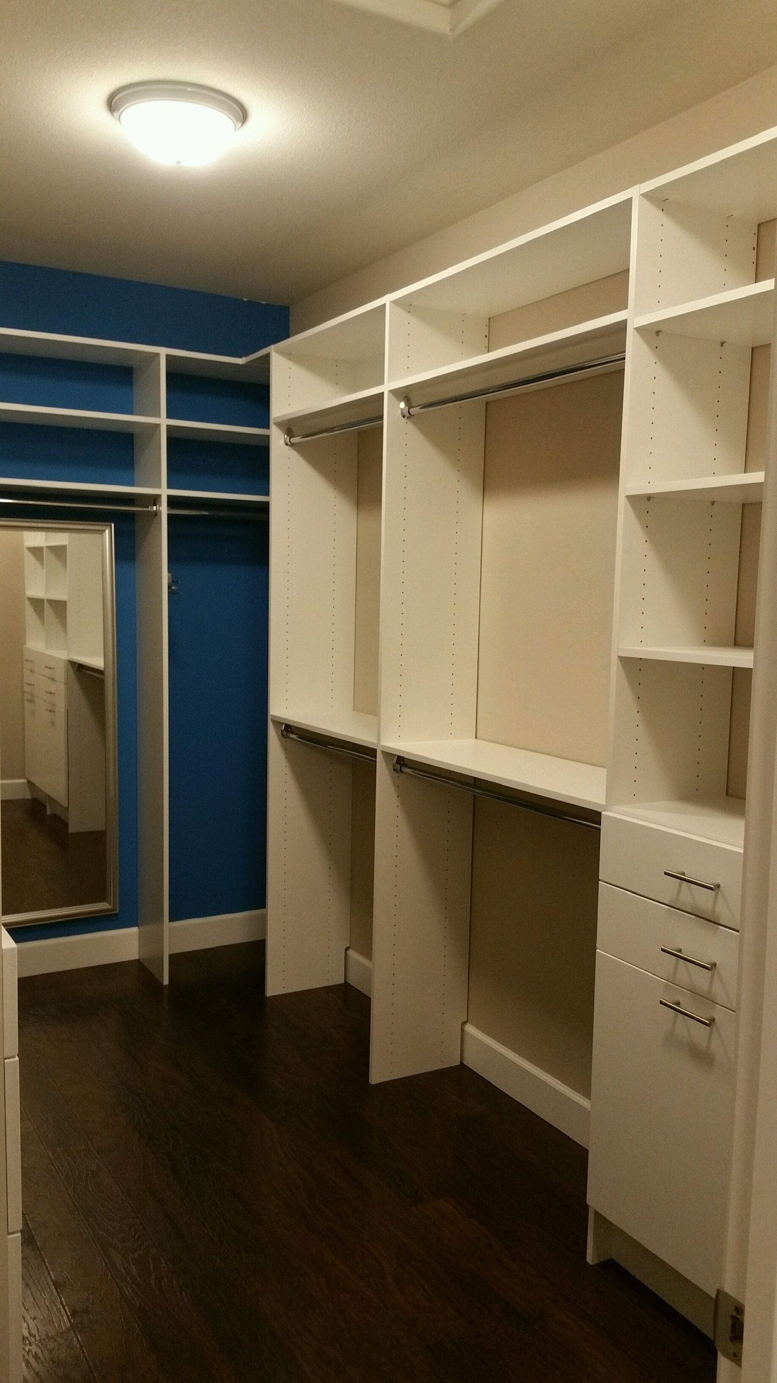 A walk in closet with lots of shelves and a mirror.