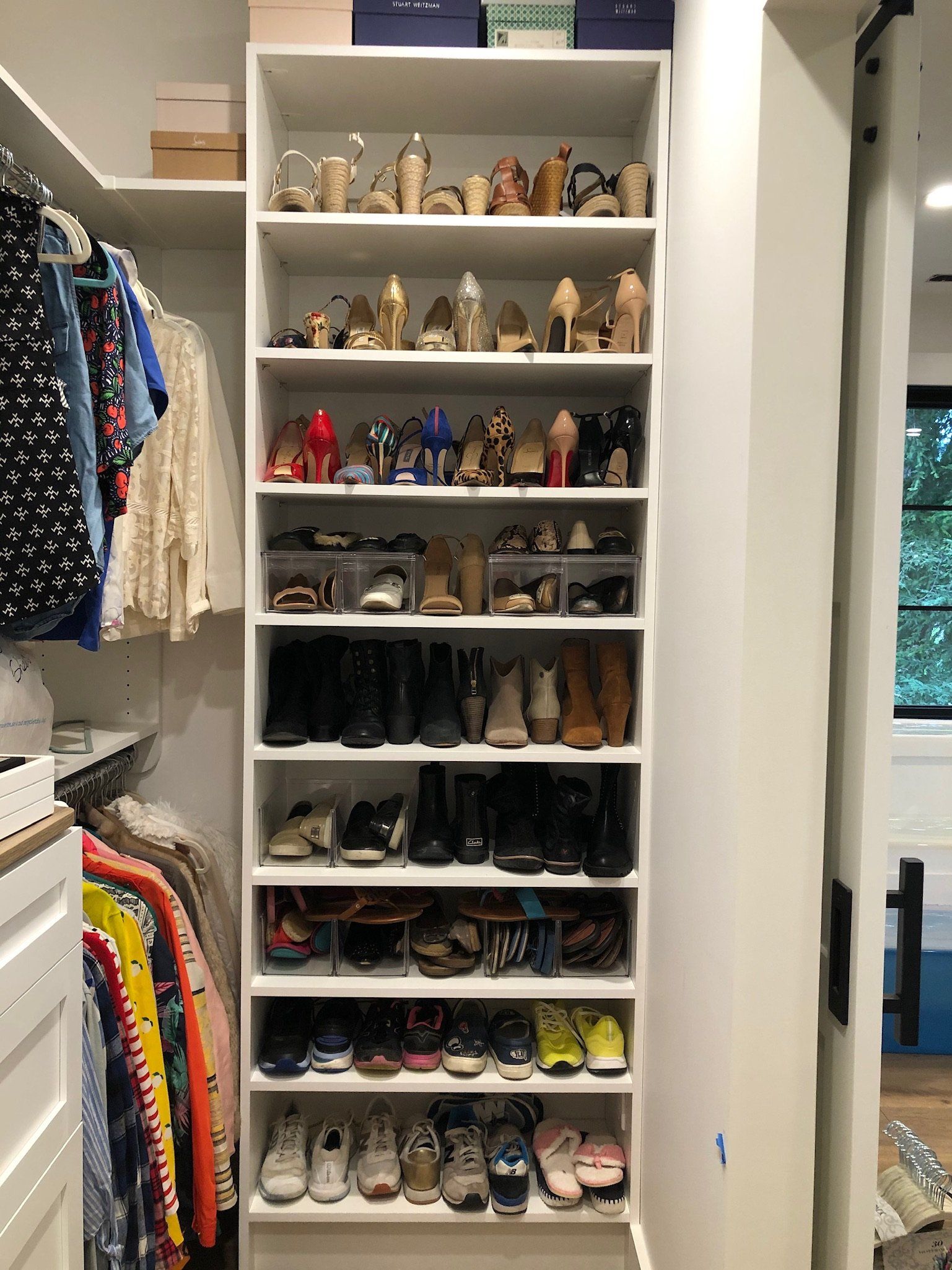 A walk in closet filled with lots of shoes and clothes.