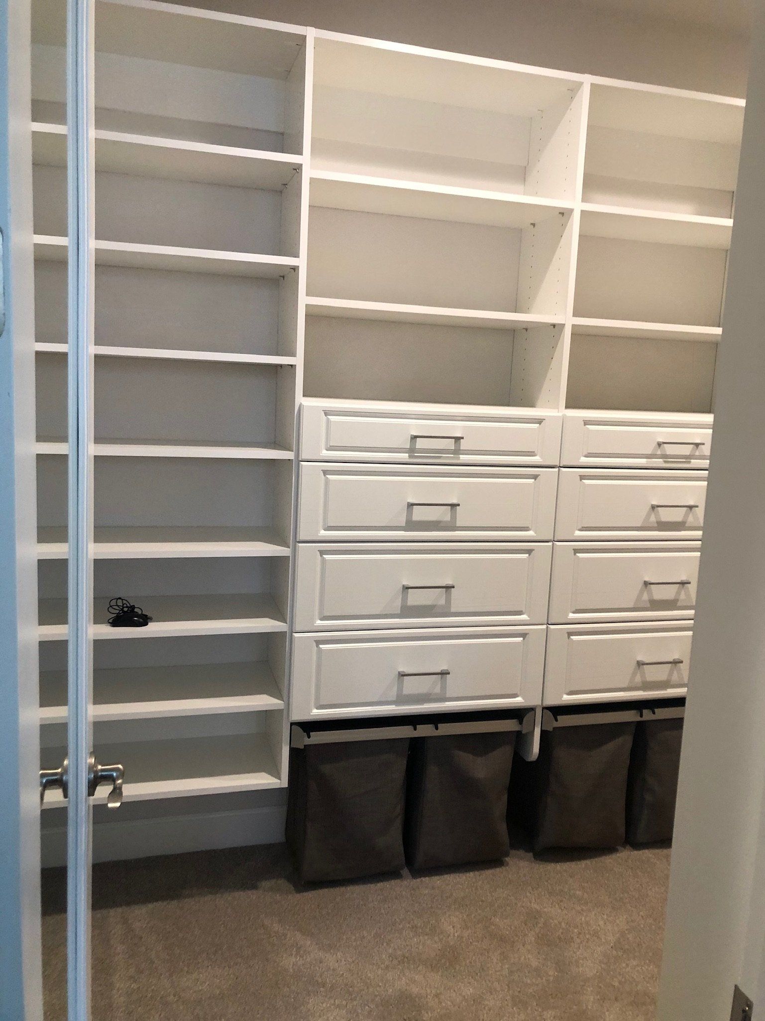 A walk in closet with lots of shelves and drawers