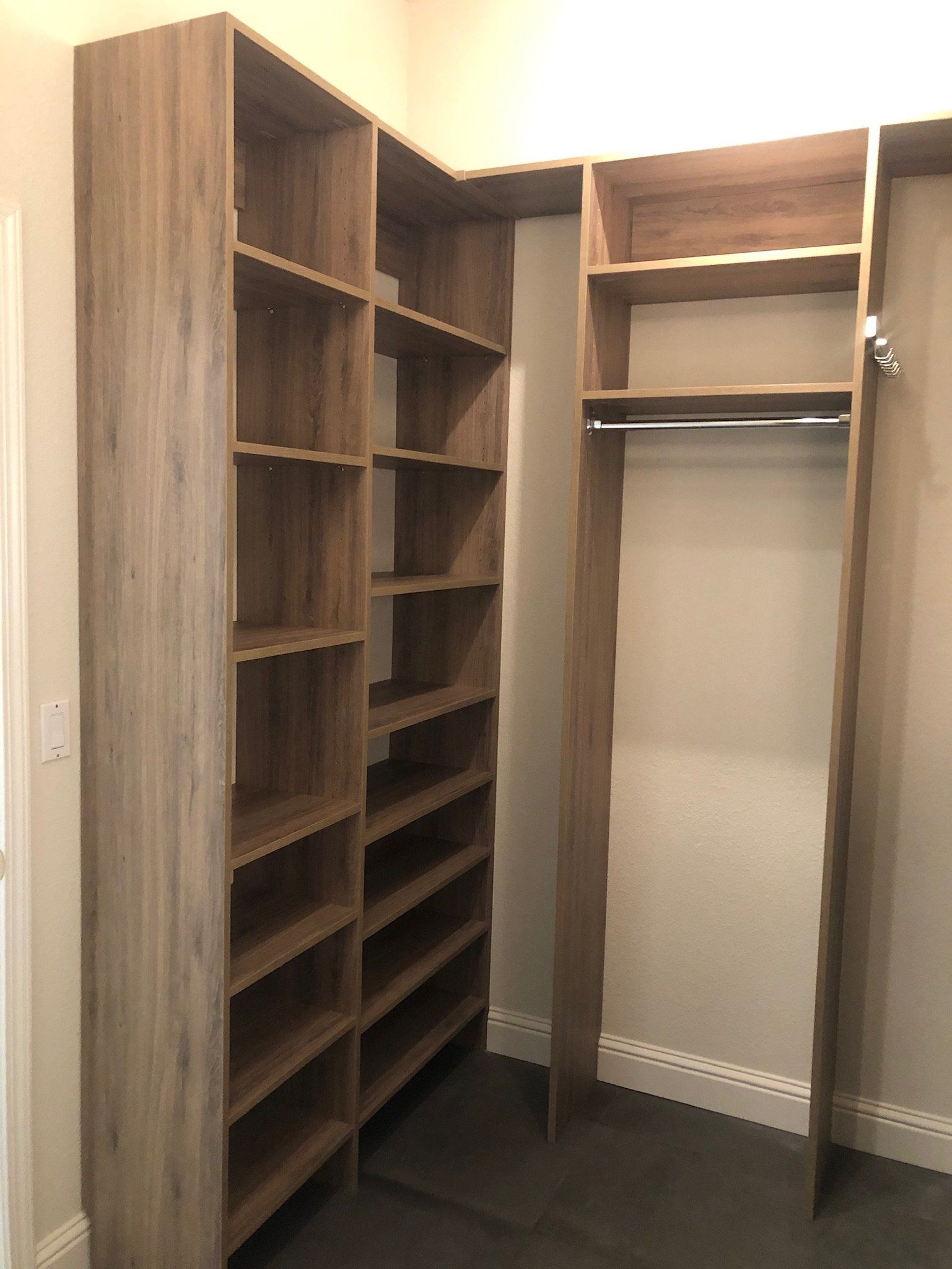 A walk in closet with wooden shelves and a hanging rack.