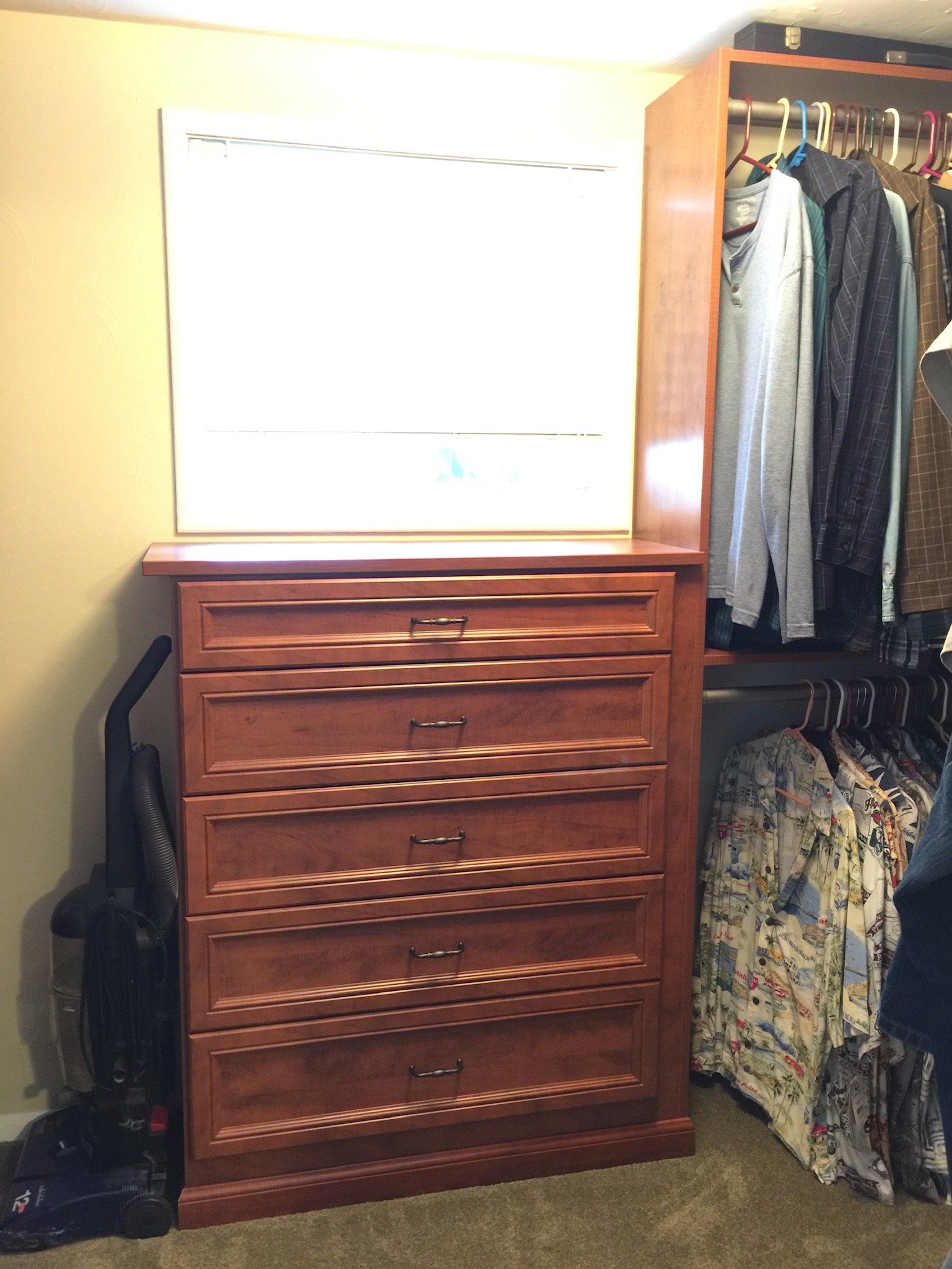 A bedroom with a dresser and a vacuum cleaner