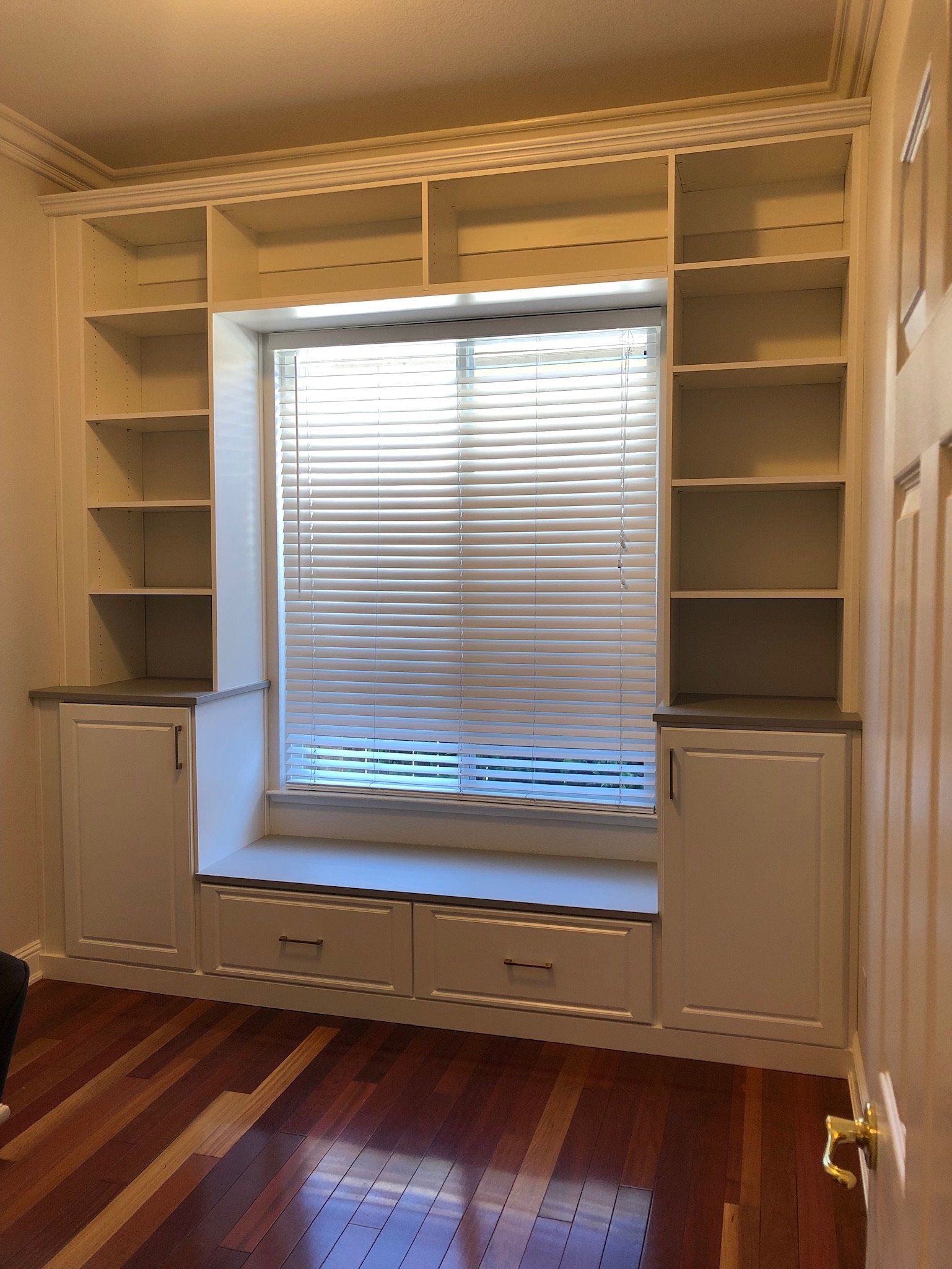 An empty room with a window seat and shelves