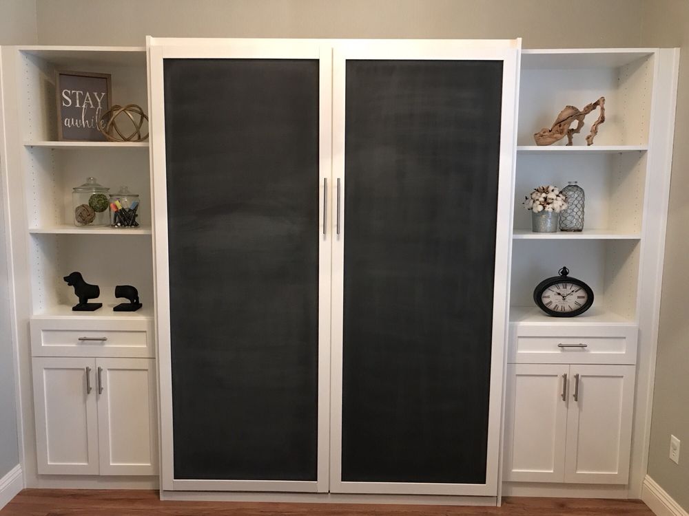 There is a chalkboard on the wall behind the cabinets.