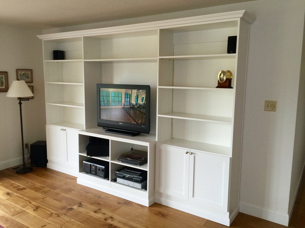 A large white entertainment center with a flat screen tv on top of it.