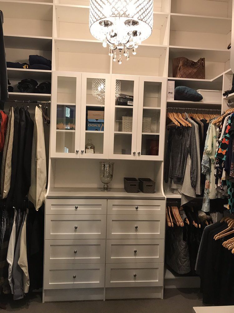A walk in closet filled with lots of clothes and a chandelier.