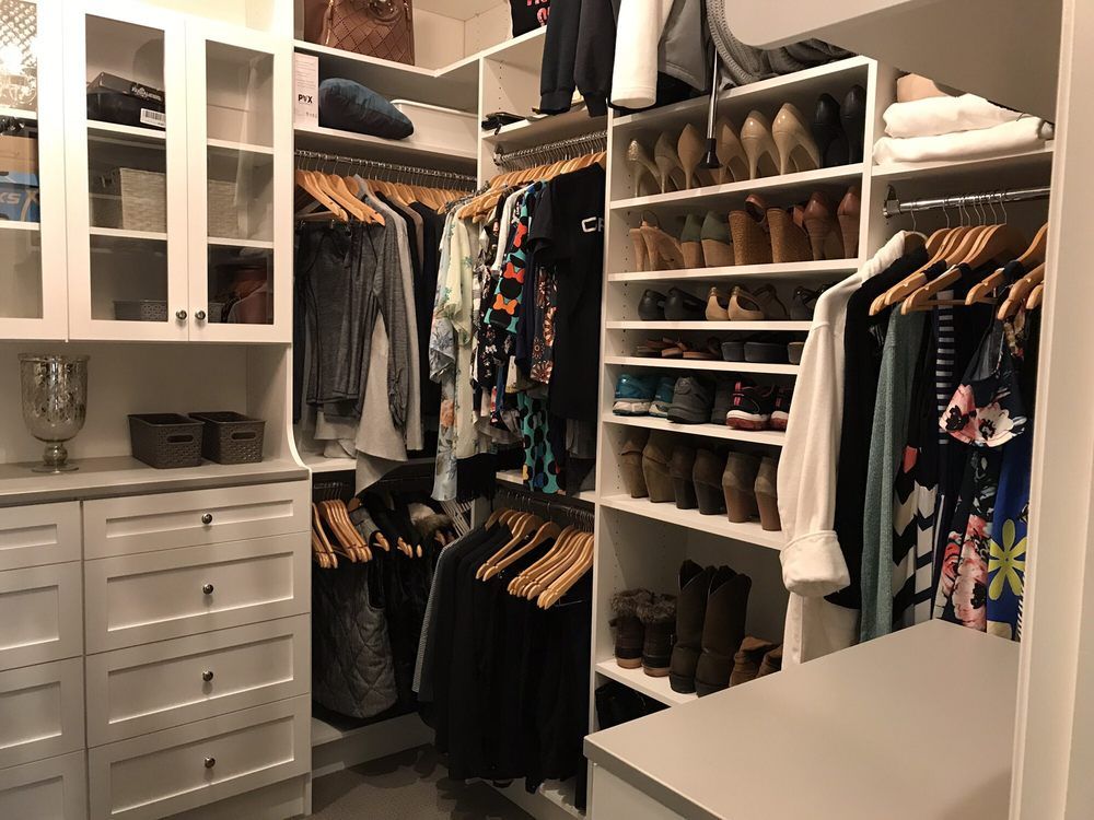 A walk in closet filled with lots of clothes and shoes.