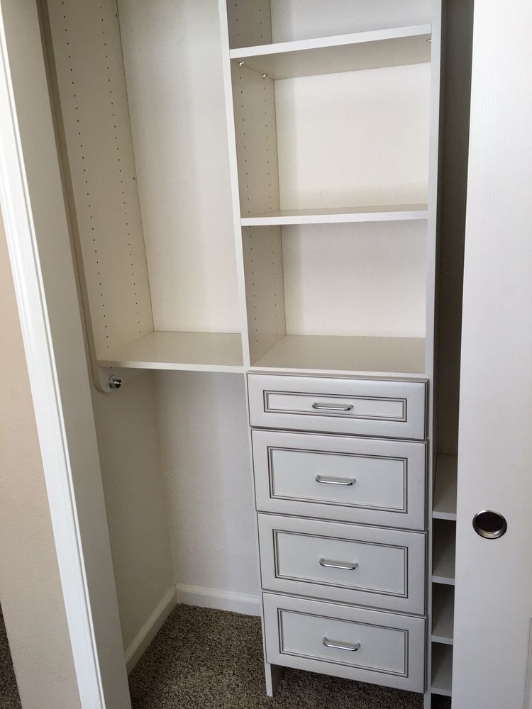 A closet with shelves and drawers and a door
