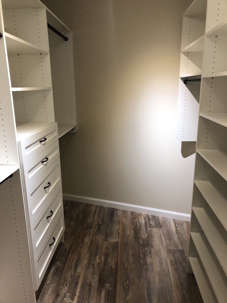 A walk in closet with lots of shelves and drawers