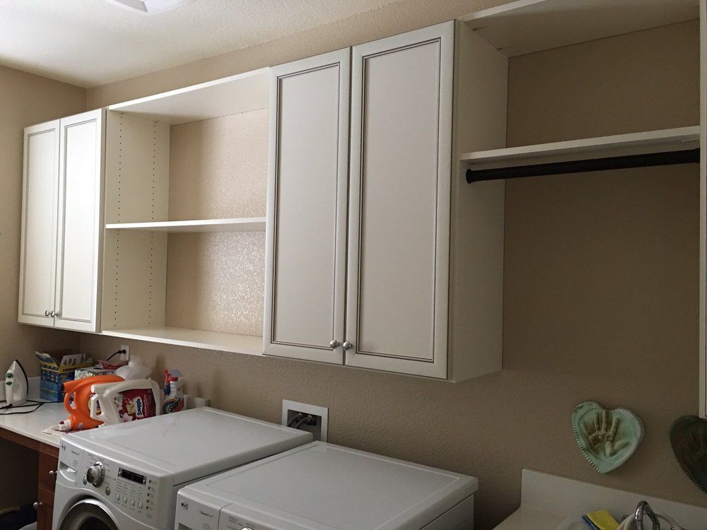 A laundry room with a washer and dryer and white cabinets.