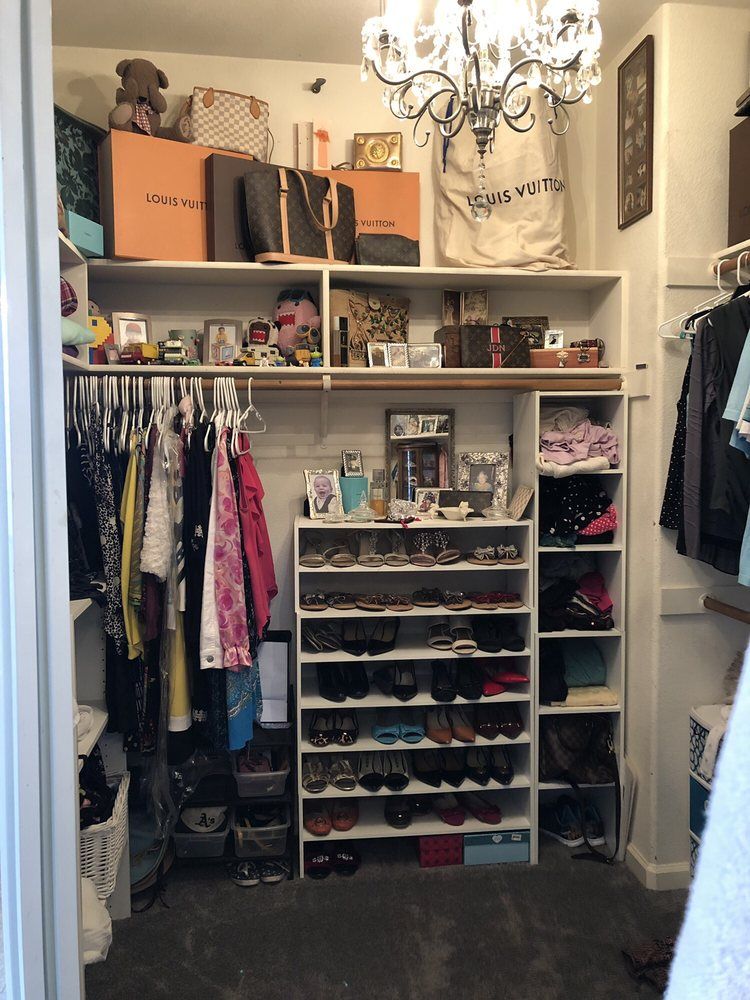 A closet filled with clothes and shoes and a chandelier.