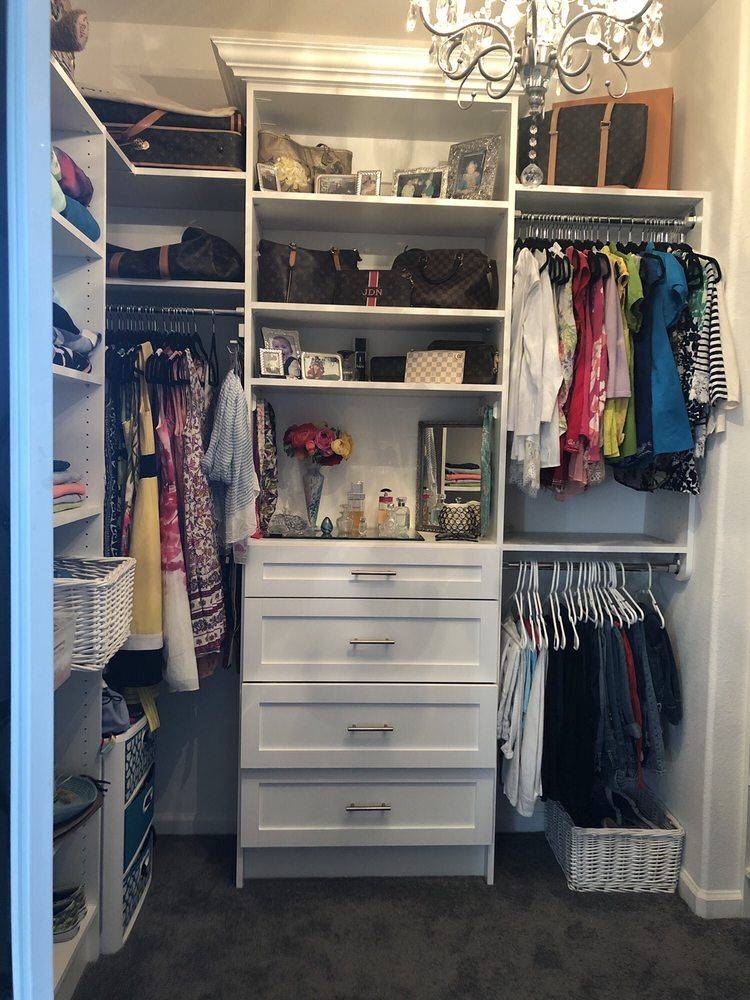 A walk in closet filled with lots of clothes and a chandelier.