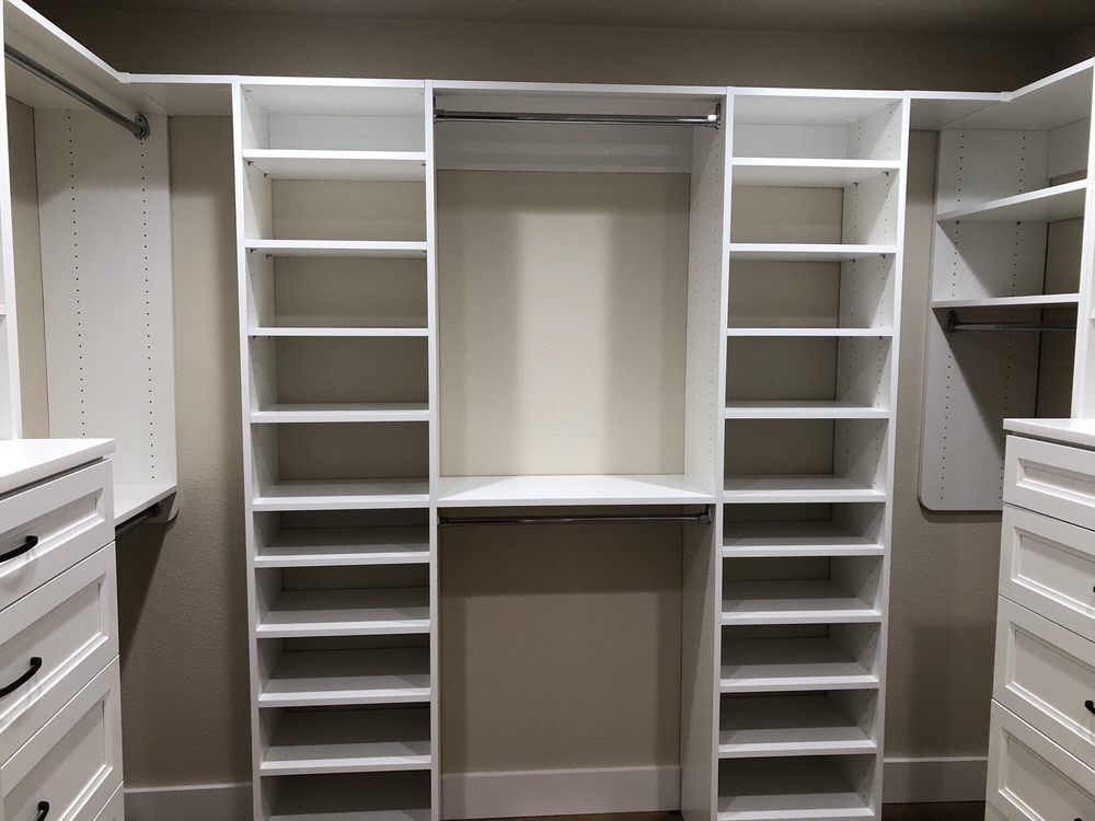 A walk in closet with lots of shelves and drawers