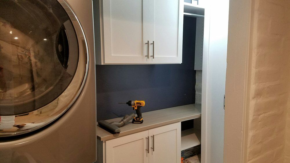 A laundry room with a washer and dryer and a drill on the counter.