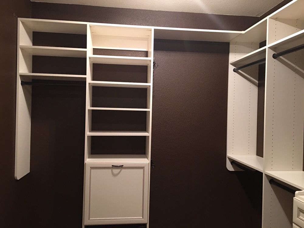 A walk in closet with brown walls and white shelves