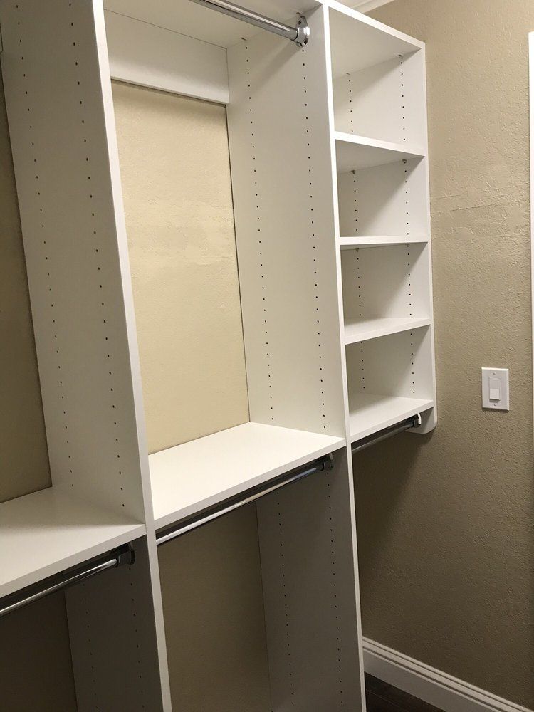 A walk in closet with white shelves and clothes racks.