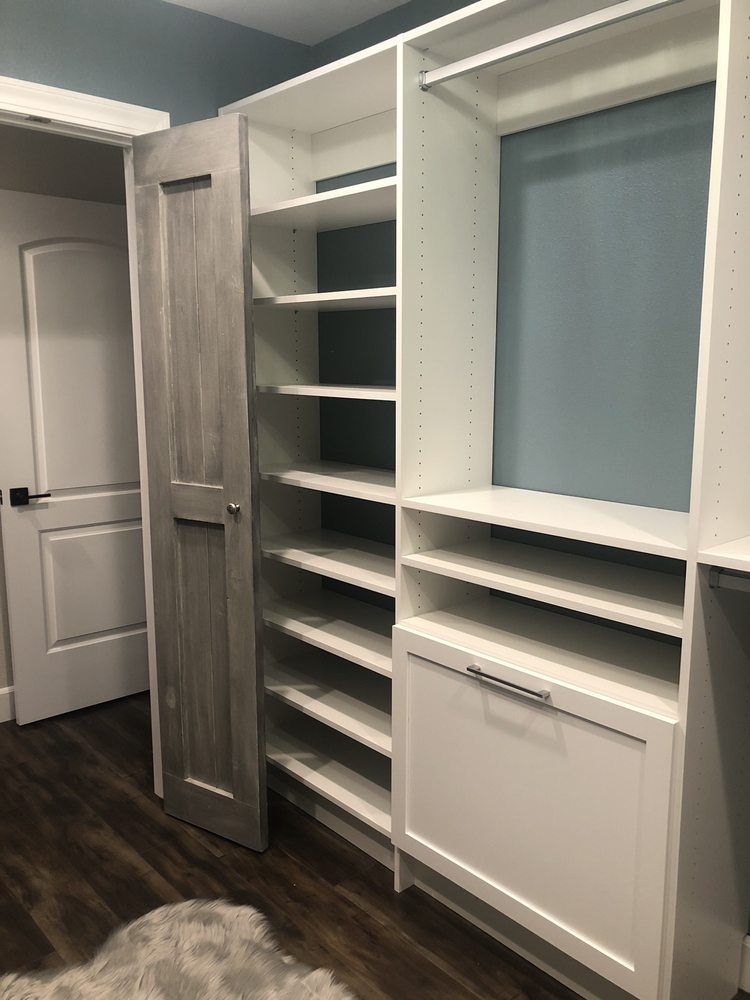A walk in closet with lots of shelves and a door.