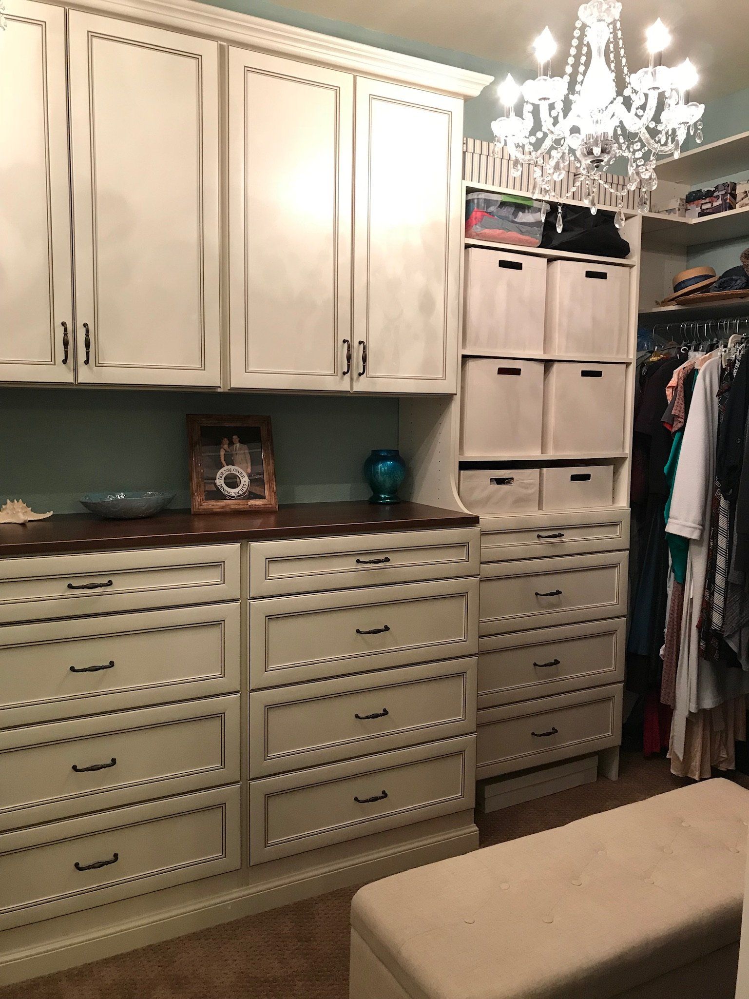A walk in closet with lots of drawers and a bench