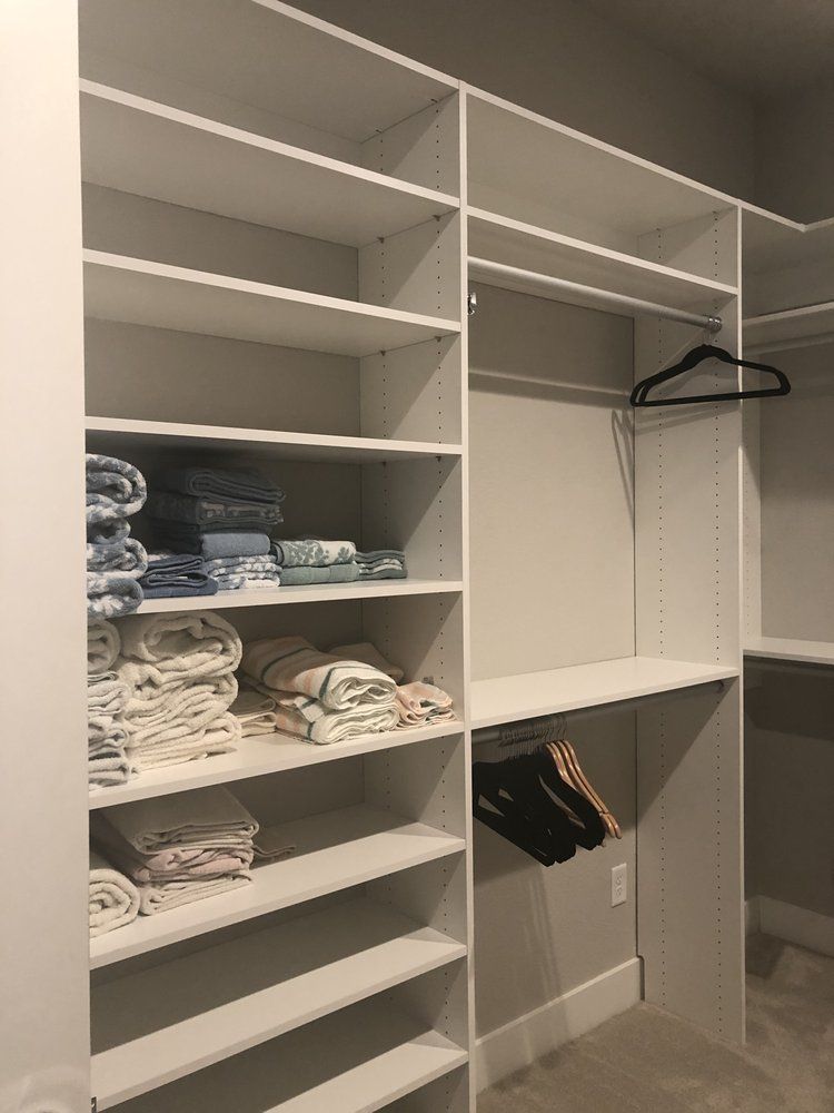 A walk in closet filled with clothes and a hanger.