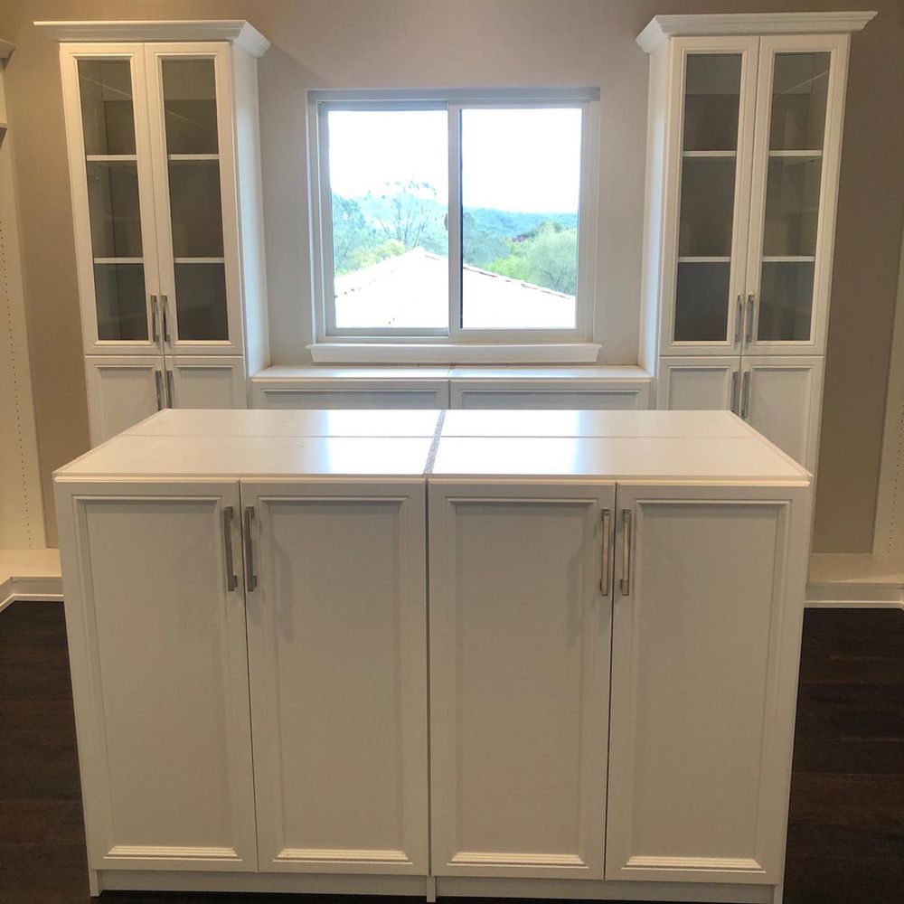 A kitchen with white cabinets and a large island in the middle of the room.