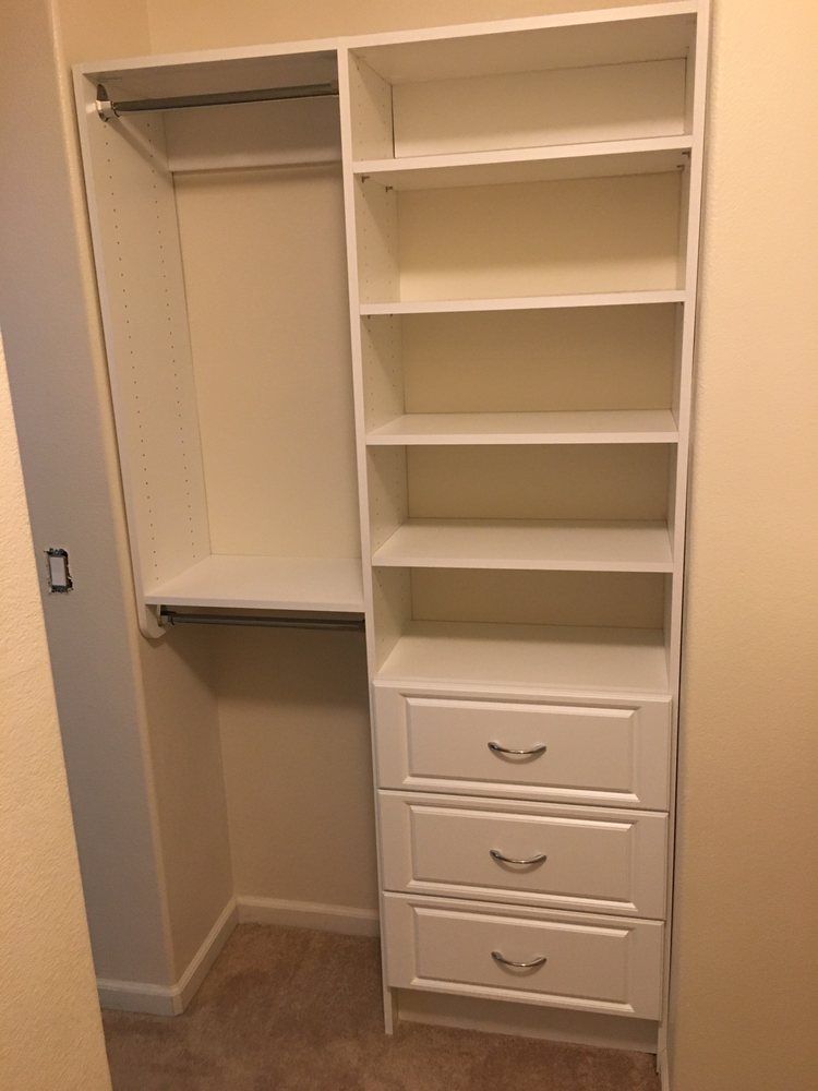 A closet with white shelves and drawers in a room.