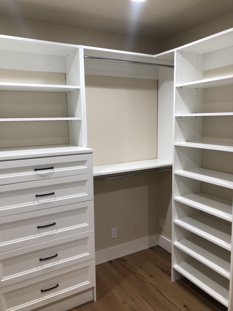 A walk in closet with lots of shelves and drawers.