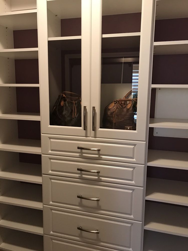 A closet with lots of shelves and drawers and a purse in it