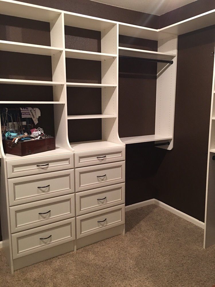 A walk in closet with lots of shelves and drawers